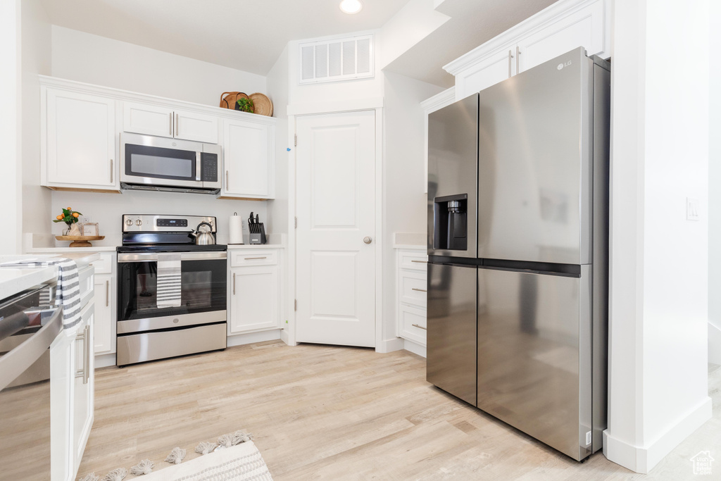 Kitchen featuring light wood-type flooring, stainless steel appliances, and white cabinetry