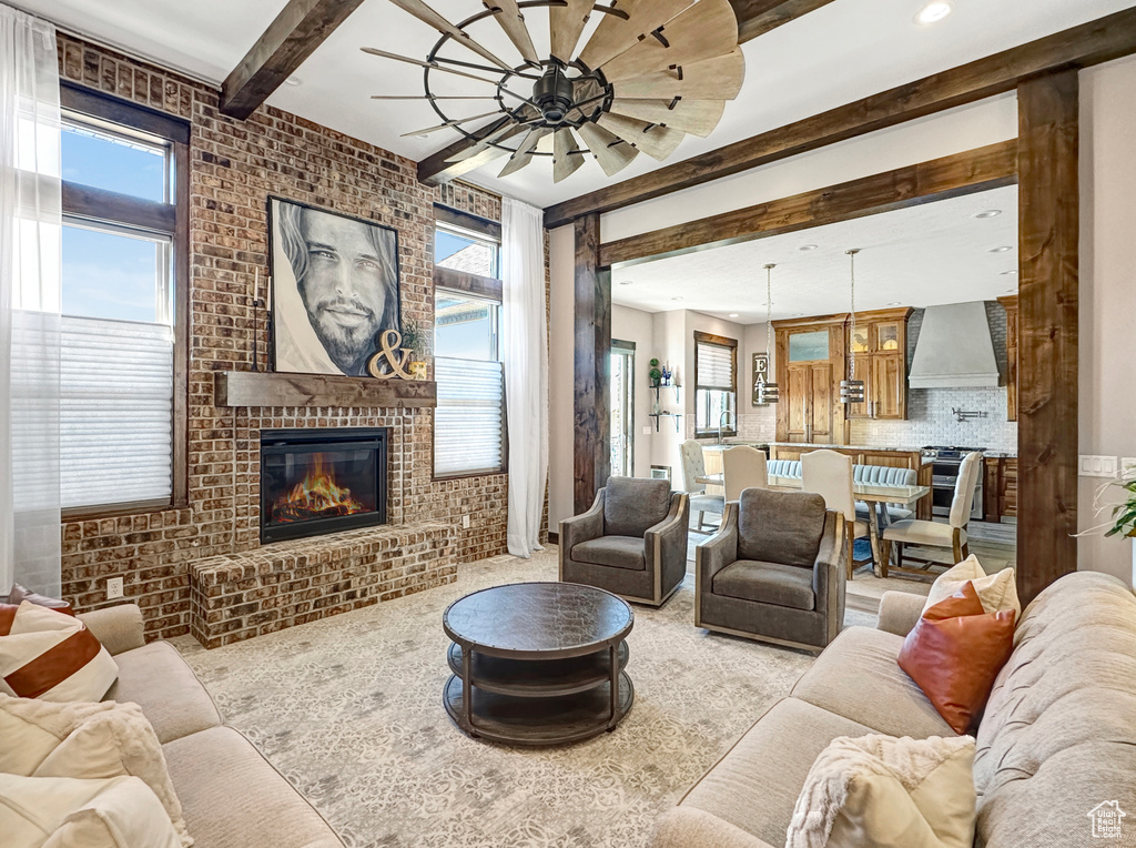 Living room with ceiling fan, a wealth of natural light, brick wall, and a fireplace