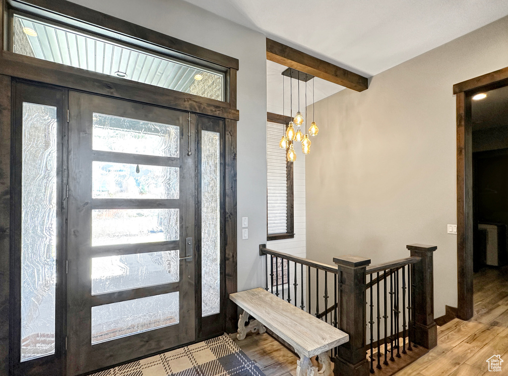 Foyer featuring a notable chandelier, beamed ceiling, and light hardwood / wood-style floors