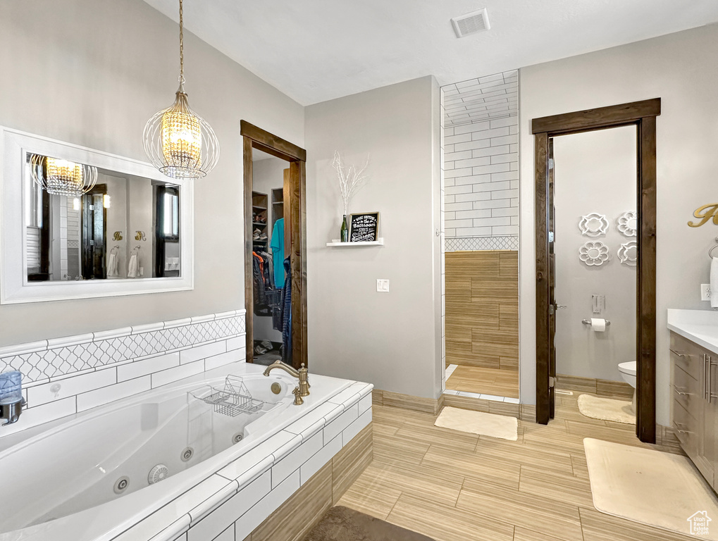 Bathroom featuring an inviting chandelier, vanity, toilet, and tile floors