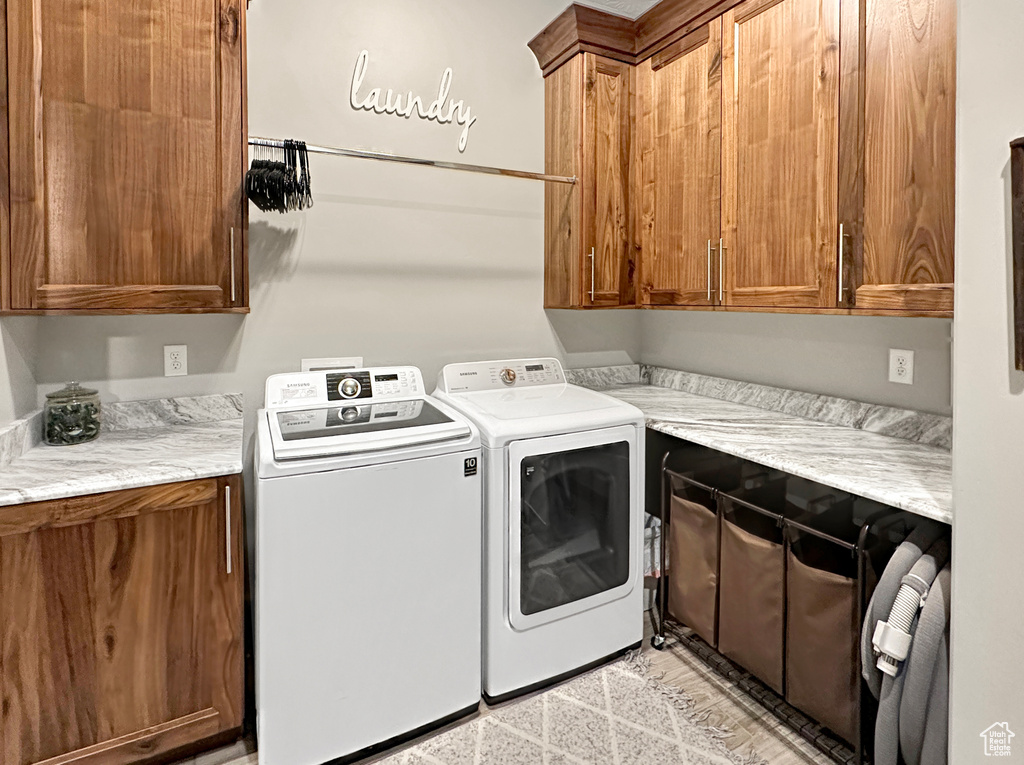 Laundry area featuring washing machine and clothes dryer, cabinets, and light tile floors
