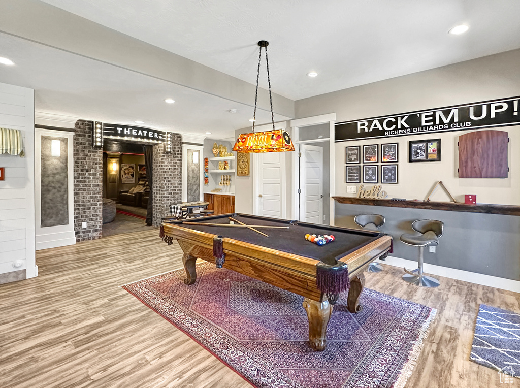 Recreation room with light wood-type flooring, brick wall, and pool table