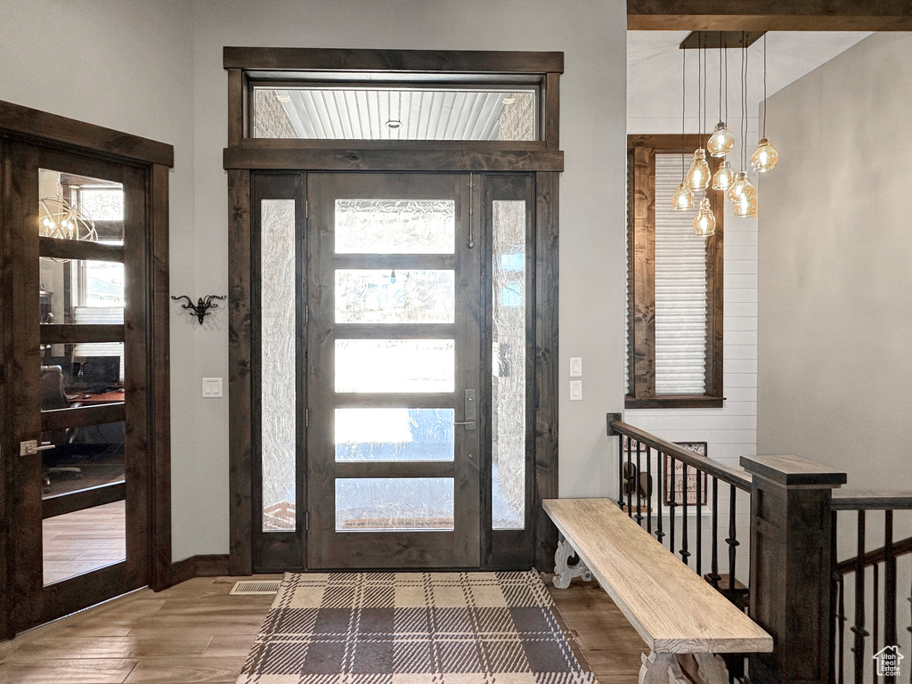 Foyer entrance with a notable chandelier, dark wood-type flooring, and a healthy amount of sunlight