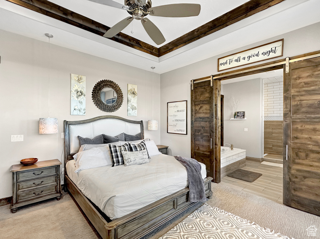 Bedroom with a barn door, light hardwood / wood-style floors, and ceiling fan