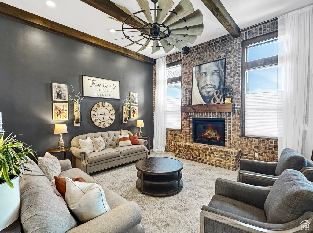 Living room with a brick fireplace, brick wall, beamed ceiling, and ceiling fan