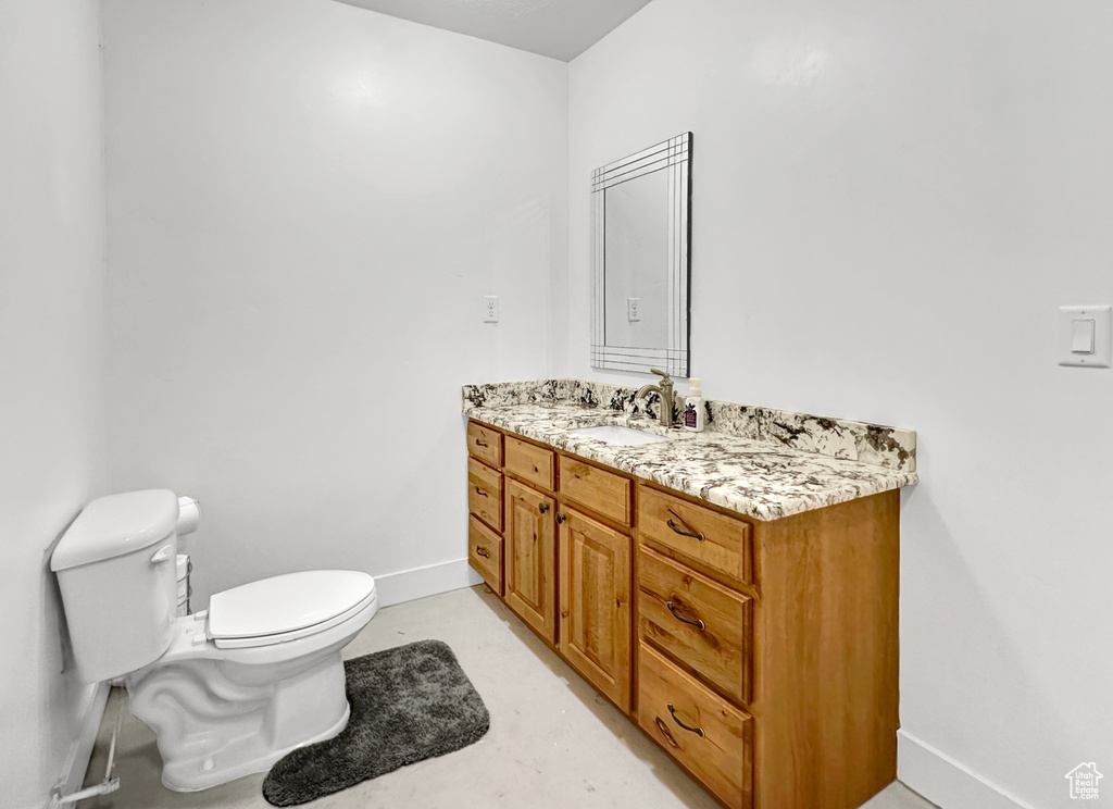 Bathroom with large vanity, toilet, and concrete floors