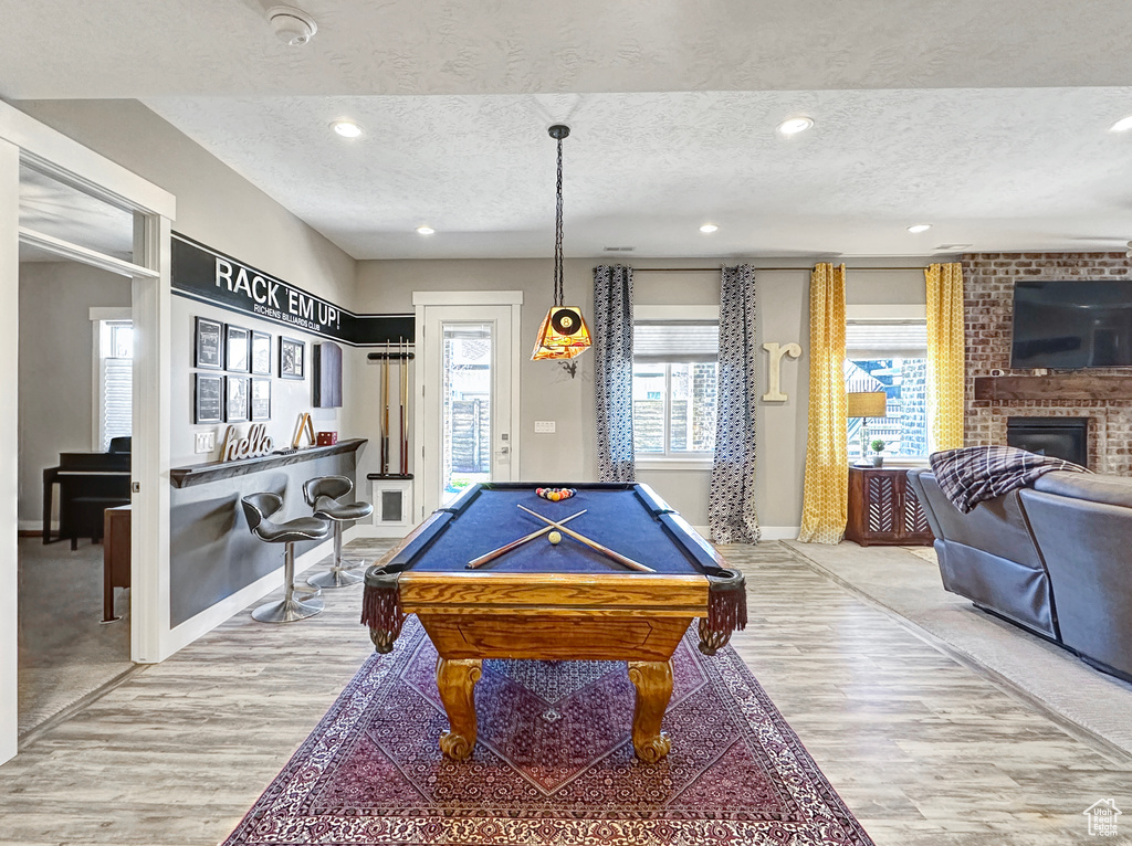 Game room featuring billiards, light colored carpet, a textured ceiling, and a fireplace