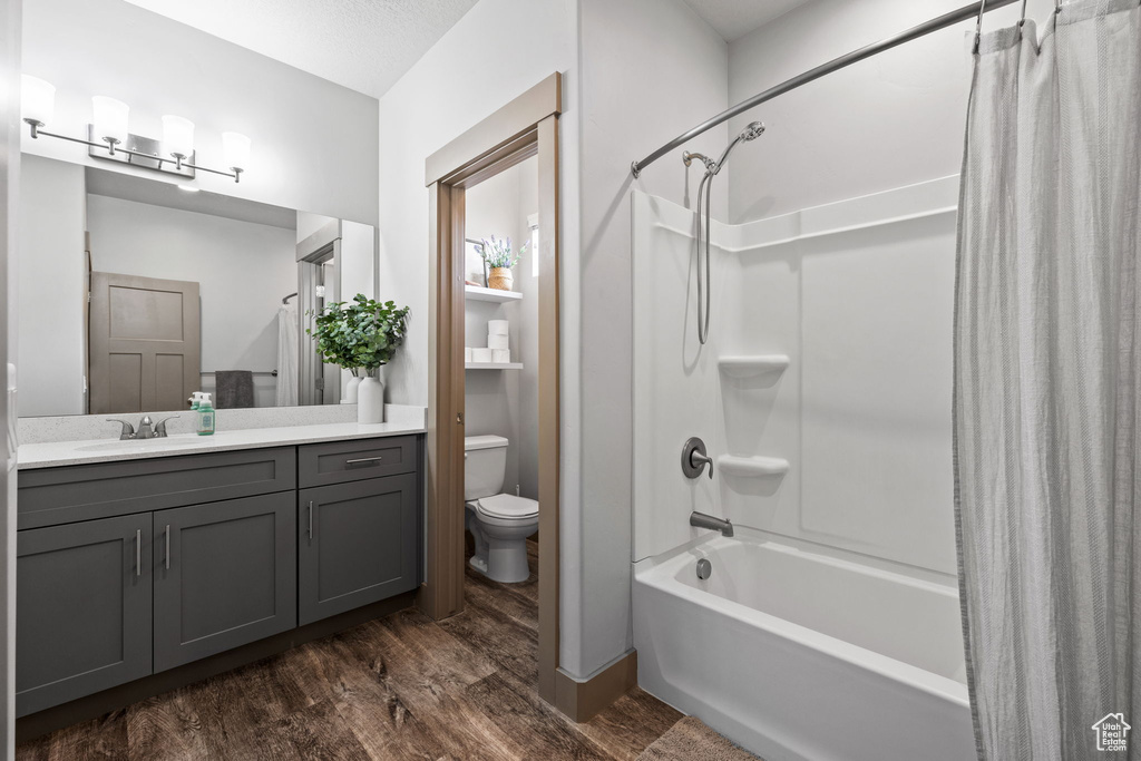 Full bathroom featuring shower / tub combo, hardwood / wood-style floors, vanity, and toilet