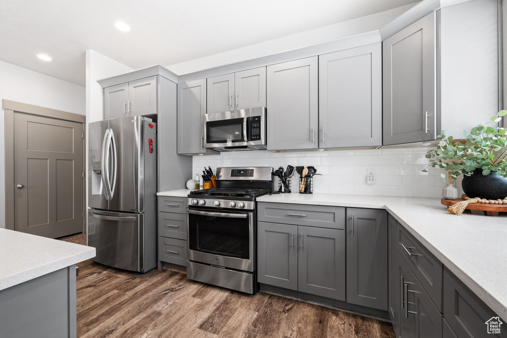 Kitchen featuring stainless steel appliances, gray cabinetry, backsplash, and dark hardwood / wood-style flooring