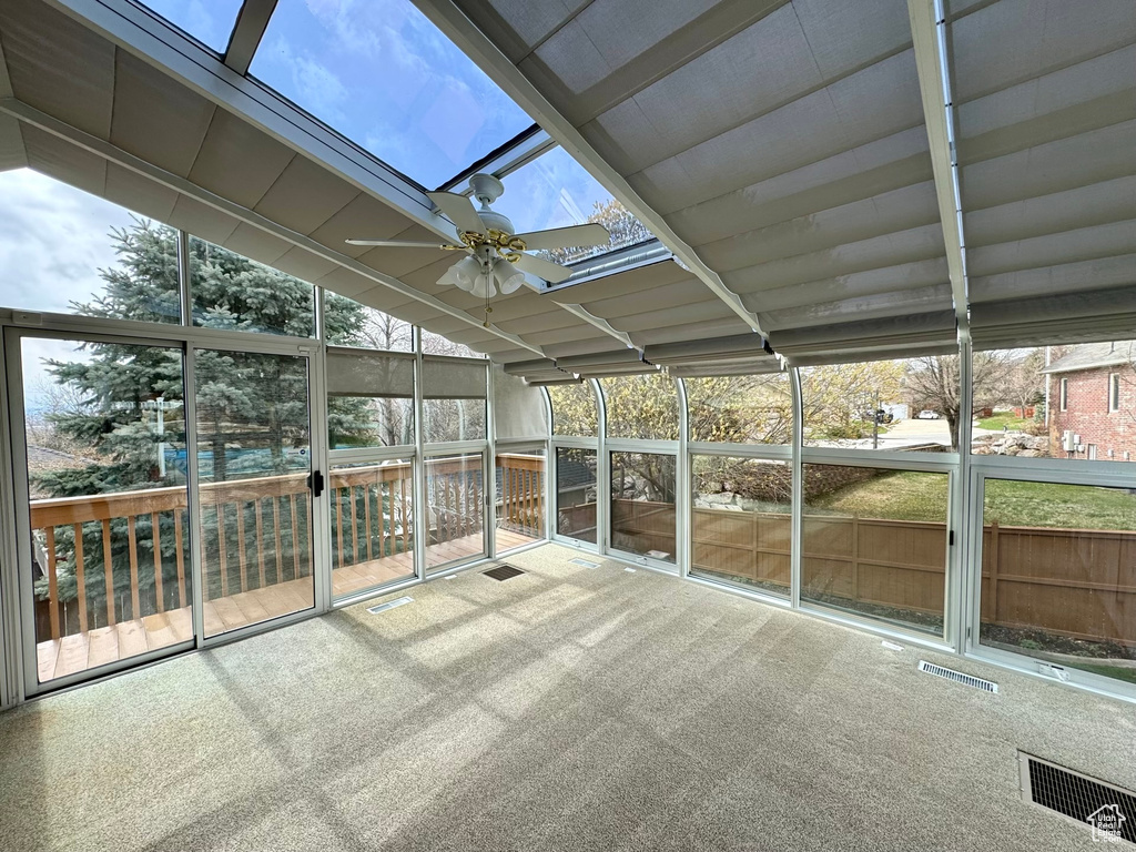 Unfurnished sunroom with a skylight and ceiling fan