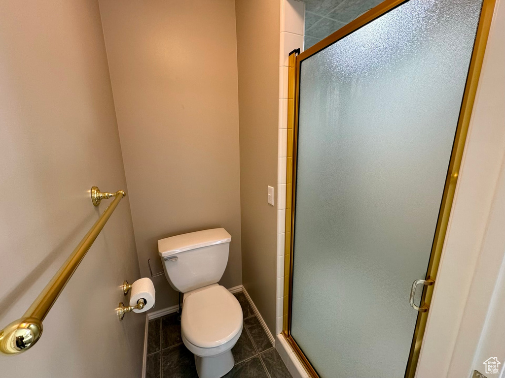 Bathroom featuring tile floors, a shower with shower door, and toilet