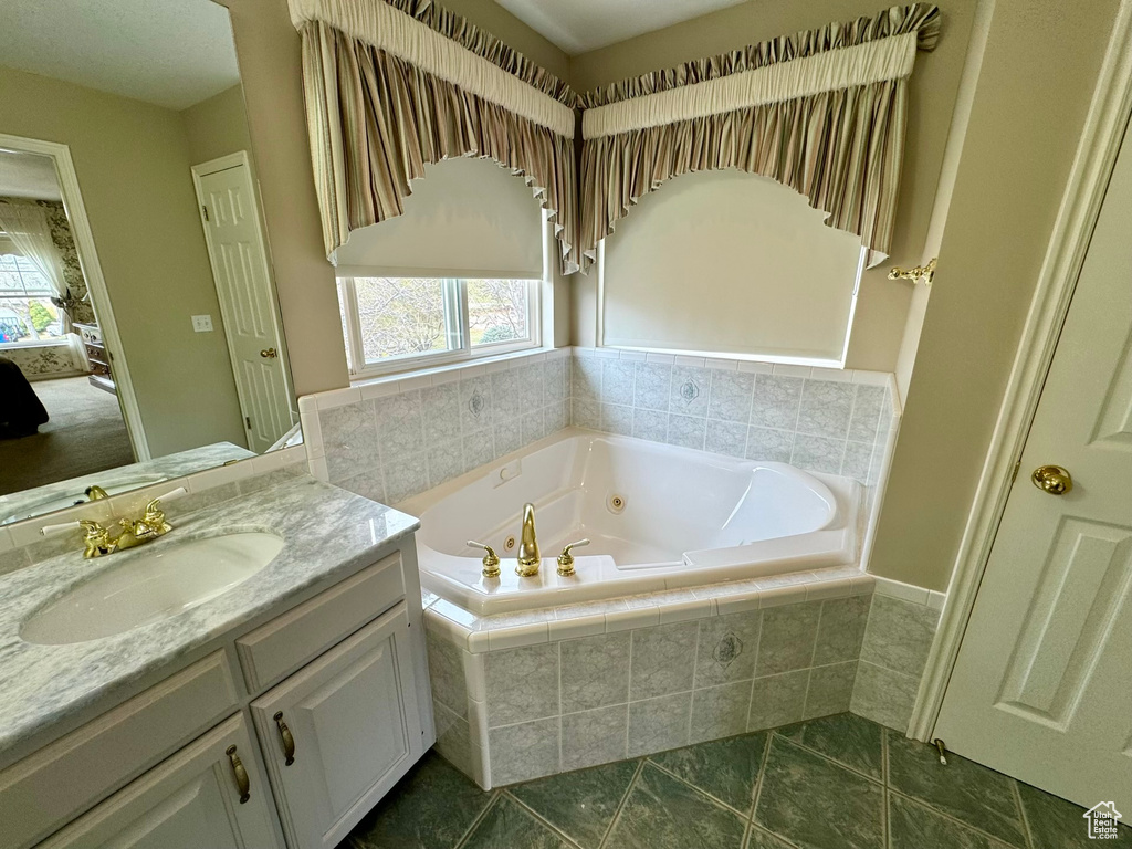 Bathroom featuring tiled tub, tile floors, and vanity