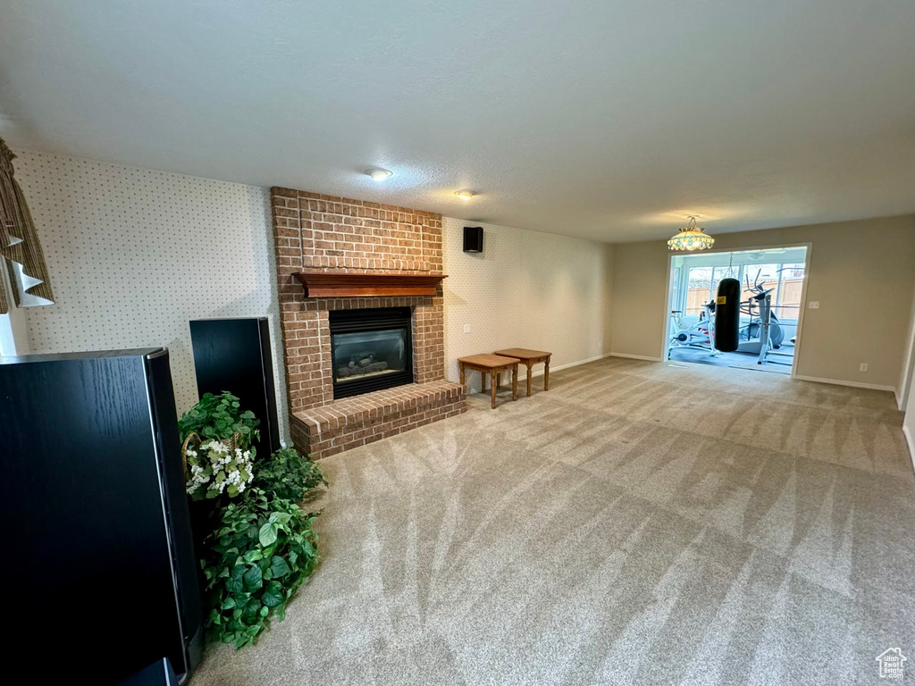 Living room featuring light colored carpet, brick wall, and a brick fireplace