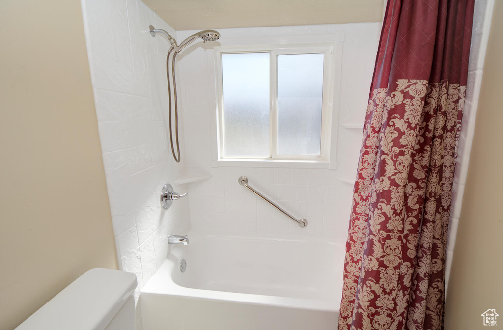 Bathroom with shower / bathtub combination with curtain and toilet