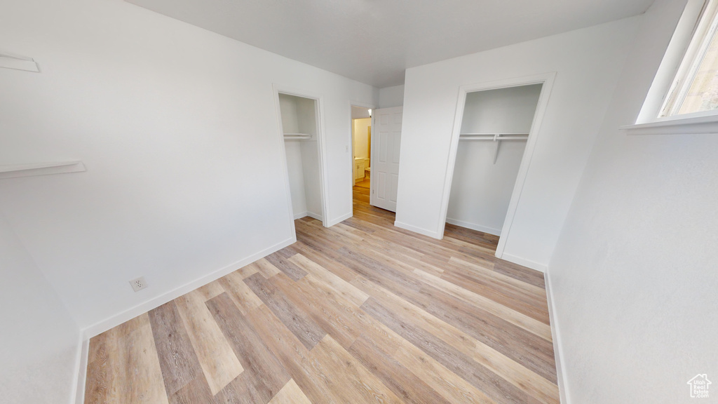 Unfurnished bedroom featuring light wood-type flooring and multiple closets