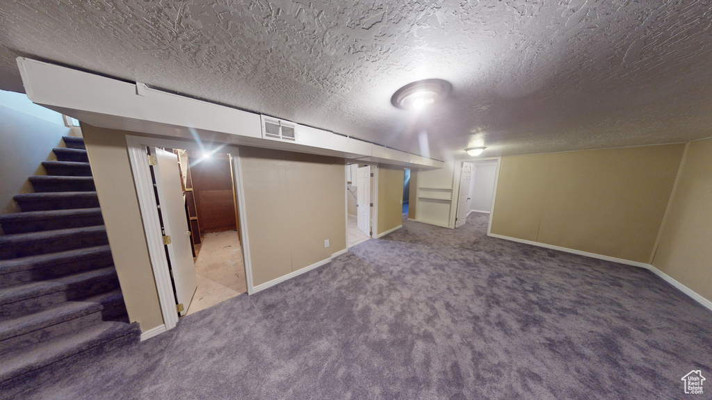Basement featuring dark carpet and a textured ceiling
