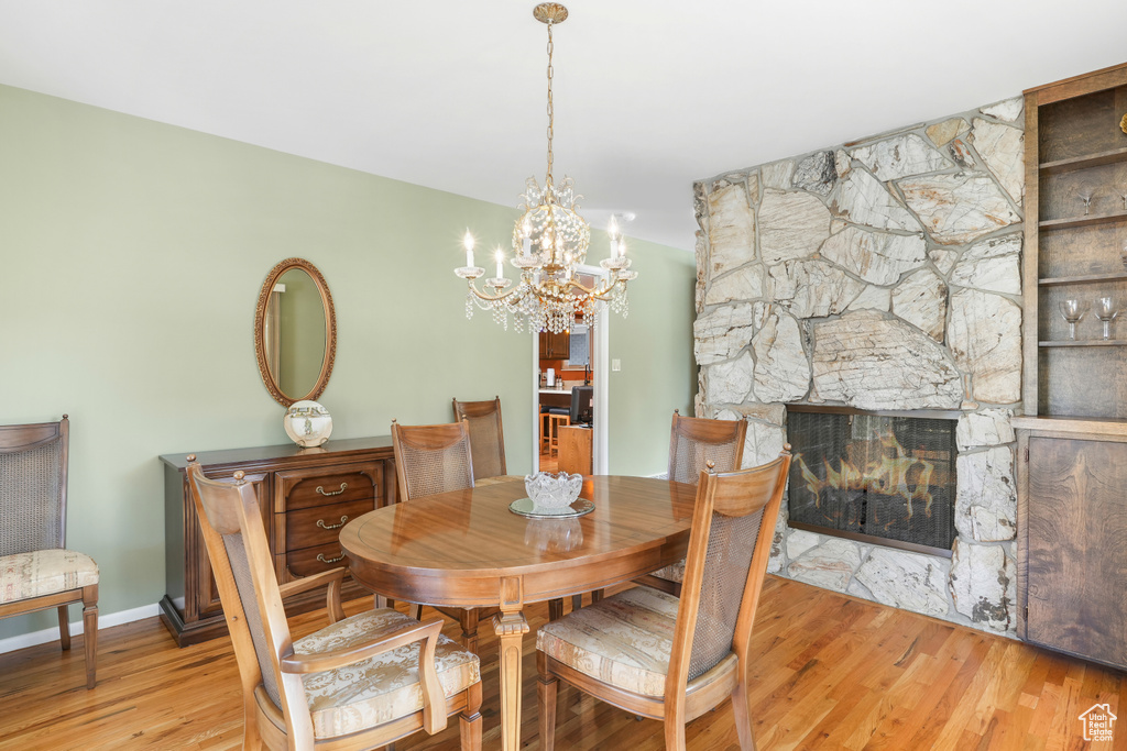 Dining area featuring an inviting chandelier, light hardwood / wood-style floors, and a fireplace
