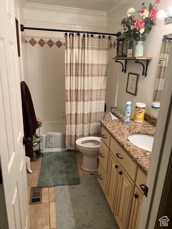 Full bathroom with vanity, shower / bath combo with shower curtain, ornamental molding, tile floors, and toilet