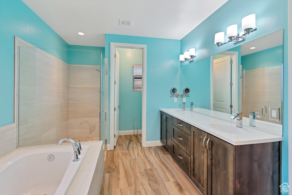 Bathroom featuring double sink, hardwood / wood-style floors, large vanity, and independent shower and bath