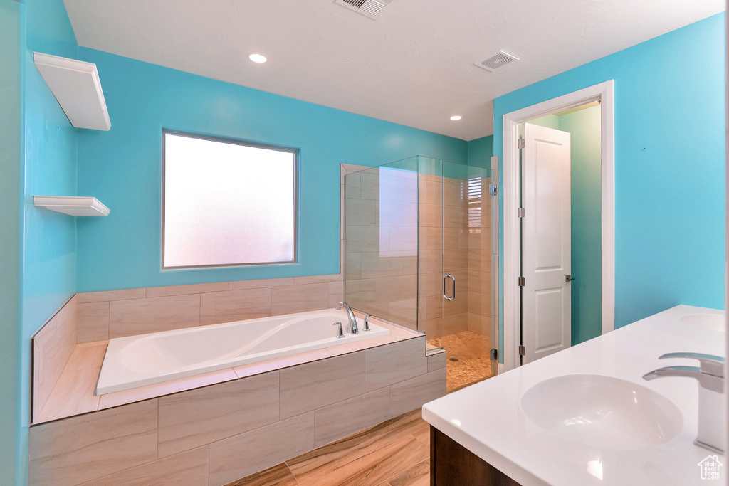 Bathroom with double vanity, hardwood / wood-style flooring, and independent shower and bath