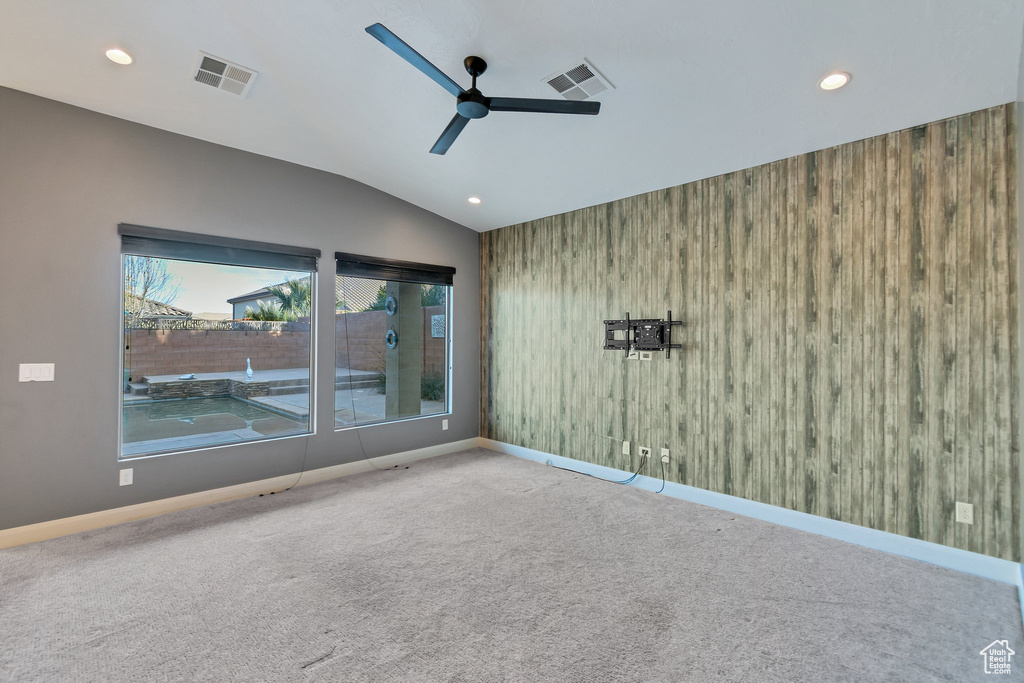 Spare room featuring ceiling fan, lofted ceiling, and light colored carpet