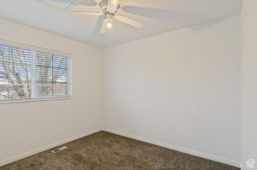 Empty room with dark colored carpet and ceiling fan