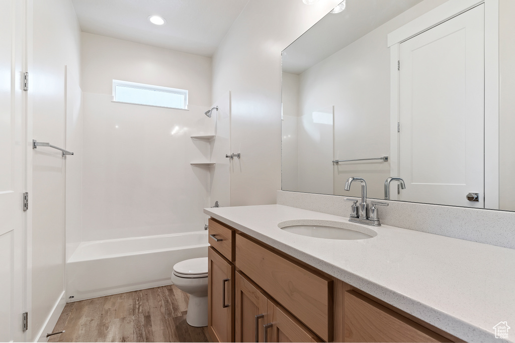 Full bathroom with oversized vanity, shower / washtub combination, toilet, and wood-type flooring