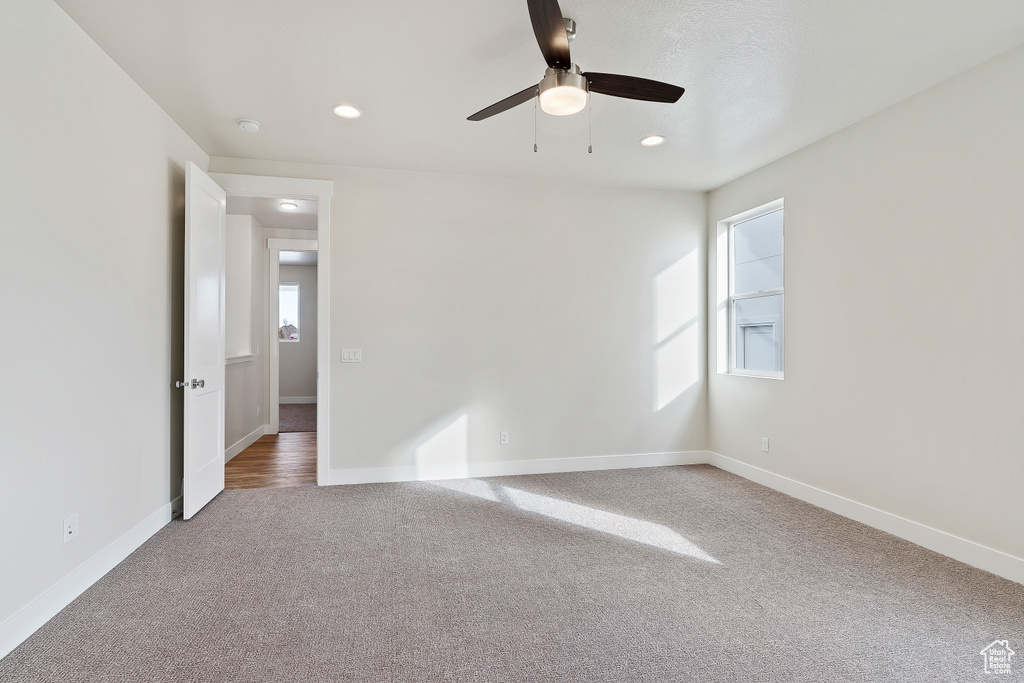 Unfurnished room with light colored carpet, ceiling fan, and a healthy amount of sunlight