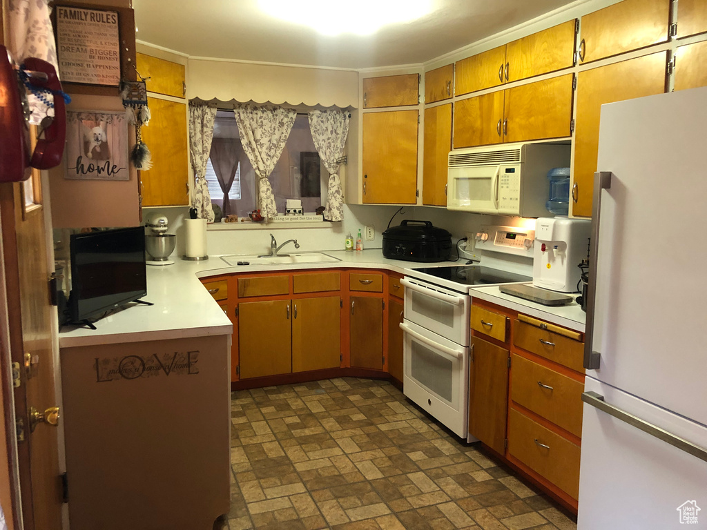 Kitchen featuring sink, white appliances, and dark tile flooring