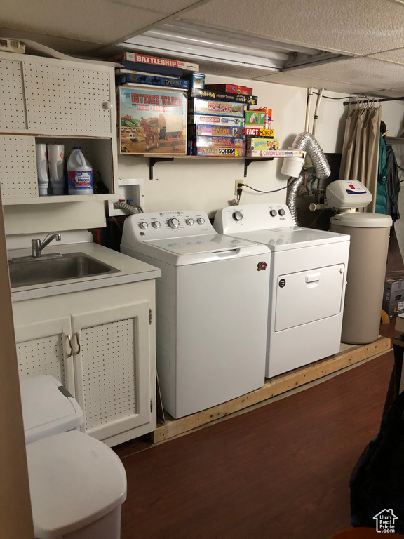 Washroom featuring sink, dark wood-type flooring, and washing machine and clothes dryer