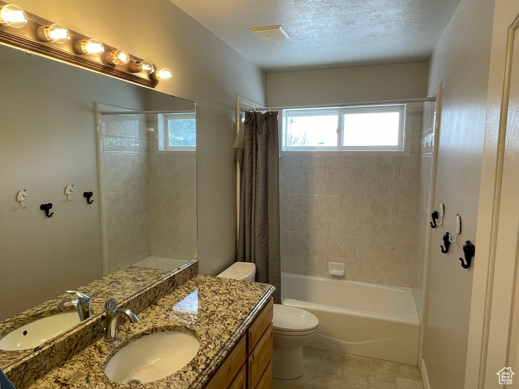 Full bathroom with vanity, shower / bath combo, a textured ceiling, tile floors, and toilet