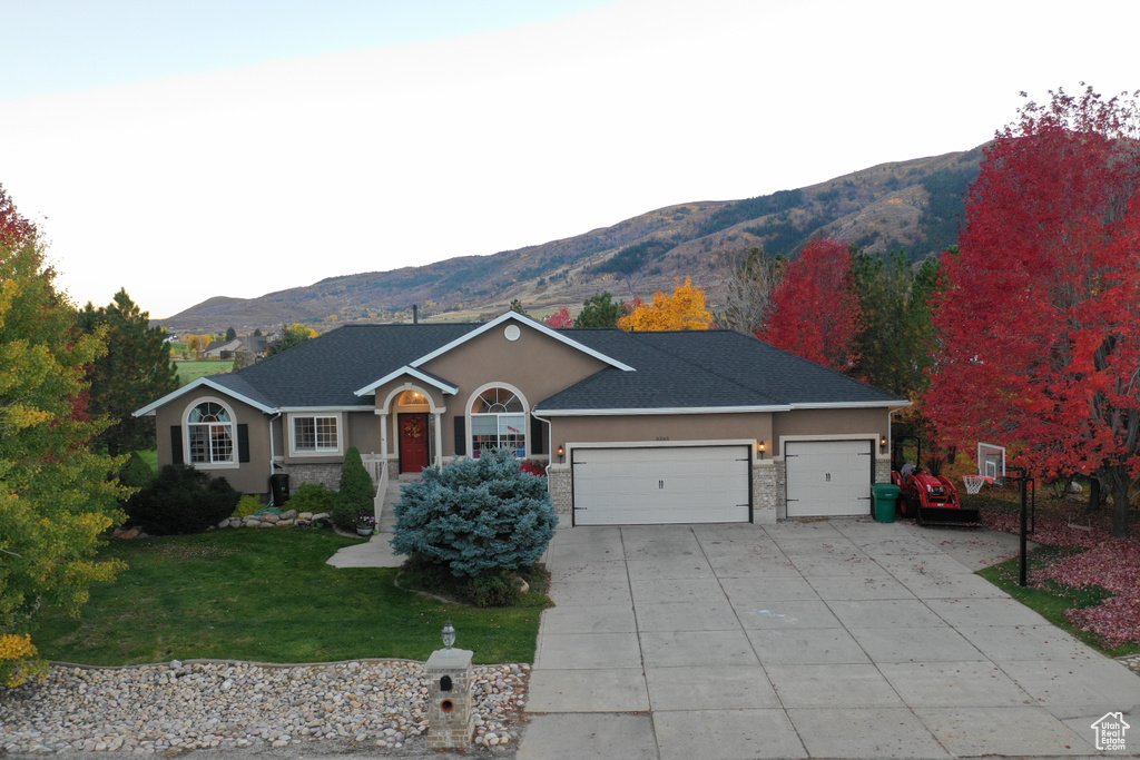 Single story home featuring a garage, a mountain view, and a front yard