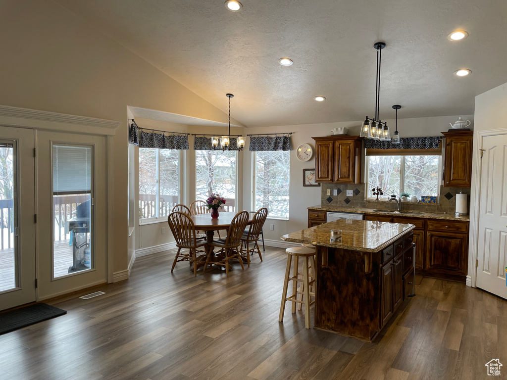 Kitchen featuring hanging light fixtures, a wealth of natural light, a breakfast bar, and dark hardwood / wood-style floors
