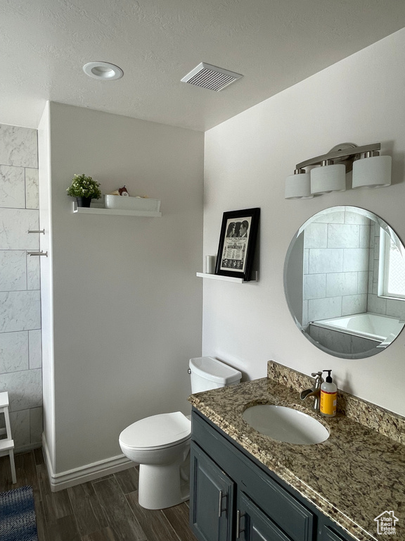 Bathroom featuring hardwood / wood-style floors, vanity, toilet, and a textured ceiling
