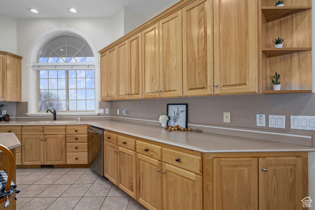 Kitchen featuring sink, light tile flooring, stainless steel dishwasher, and backsplash