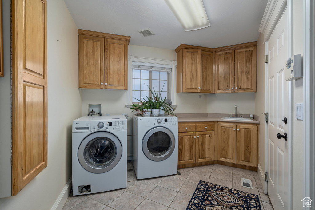 Washroom with cabinets, light tile flooring, sink, and separate washer and dryer