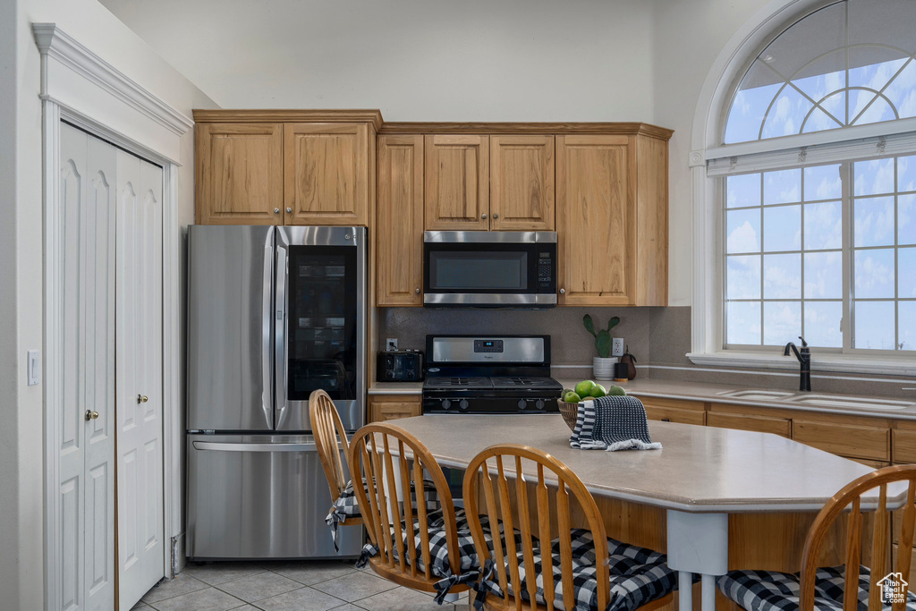 Kitchen featuring appliances with stainless steel finishes, sink, light tile floors, and tasteful backsplash