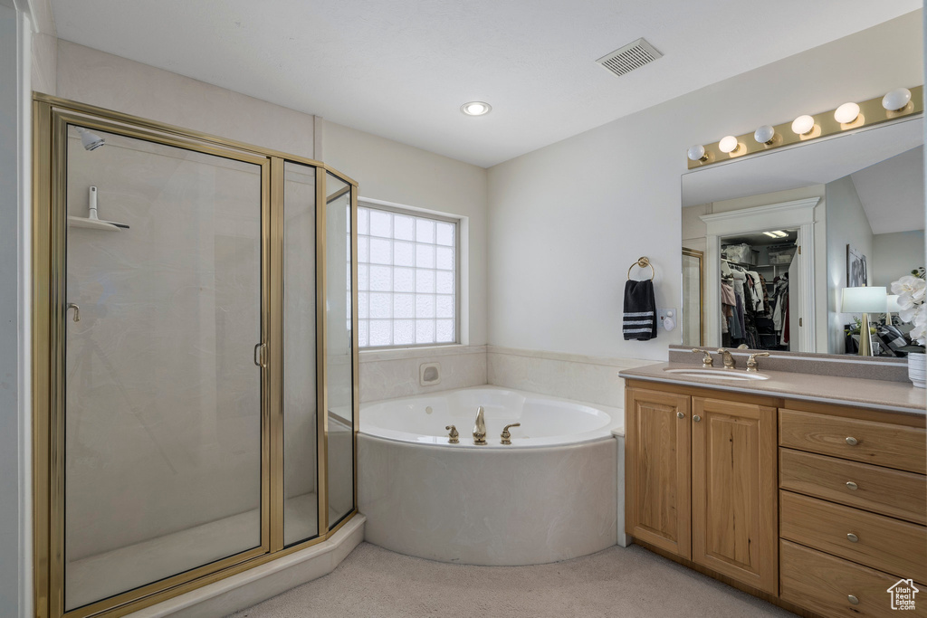 Bathroom featuring large vanity and shower with separate bathtub