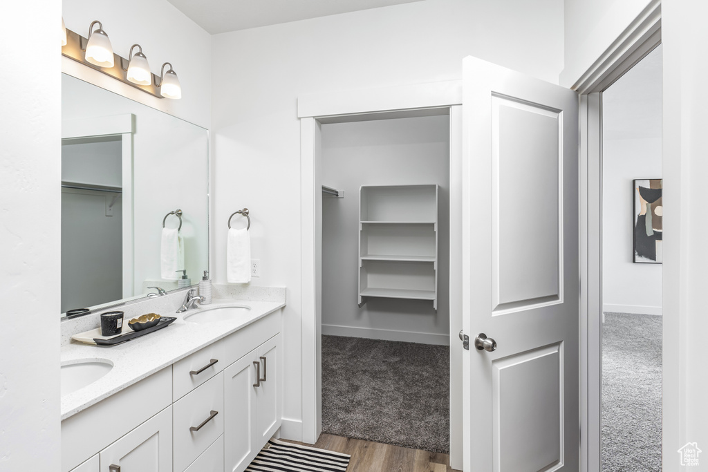 Bathroom with double sink, oversized vanity, and hardwood / wood-style flooring