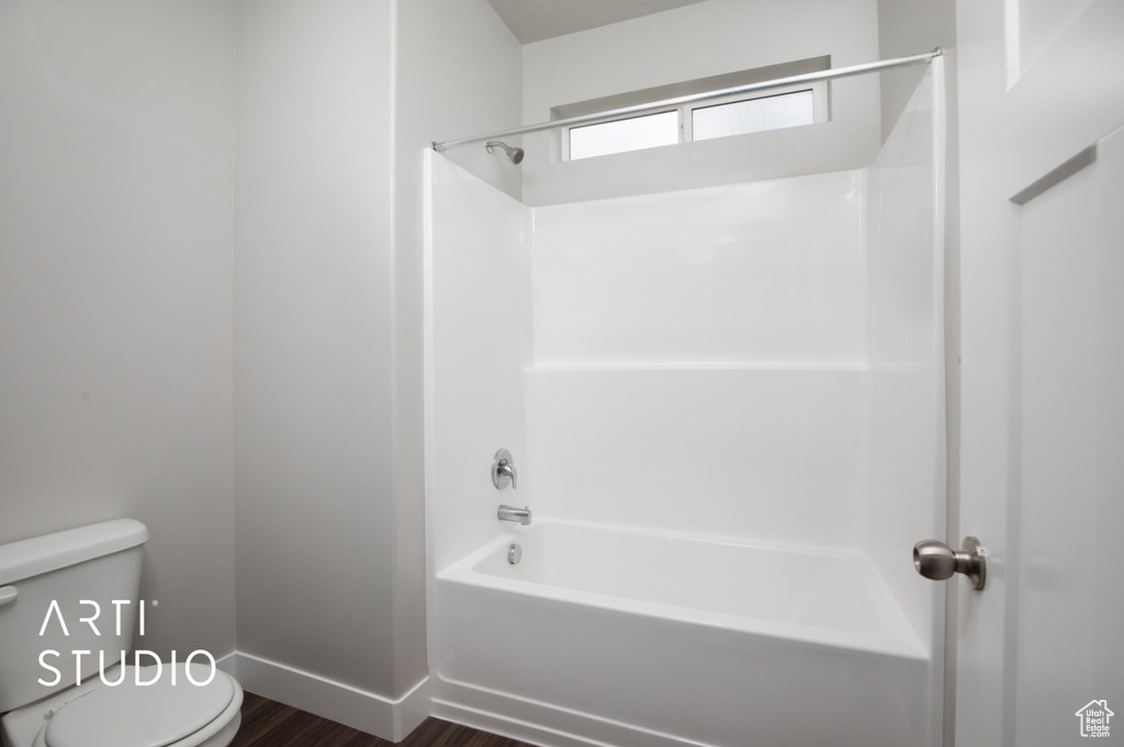 Bathroom featuring tub / shower combination, toilet, and hardwood / wood-style floors