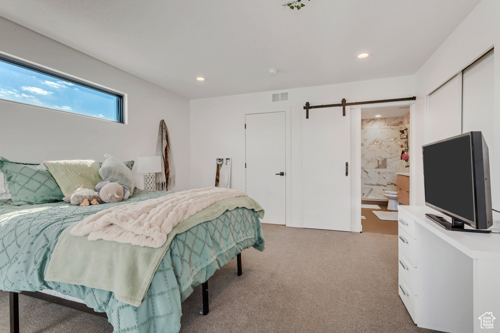 Carpeted bedroom featuring ensuite bath and a barn door