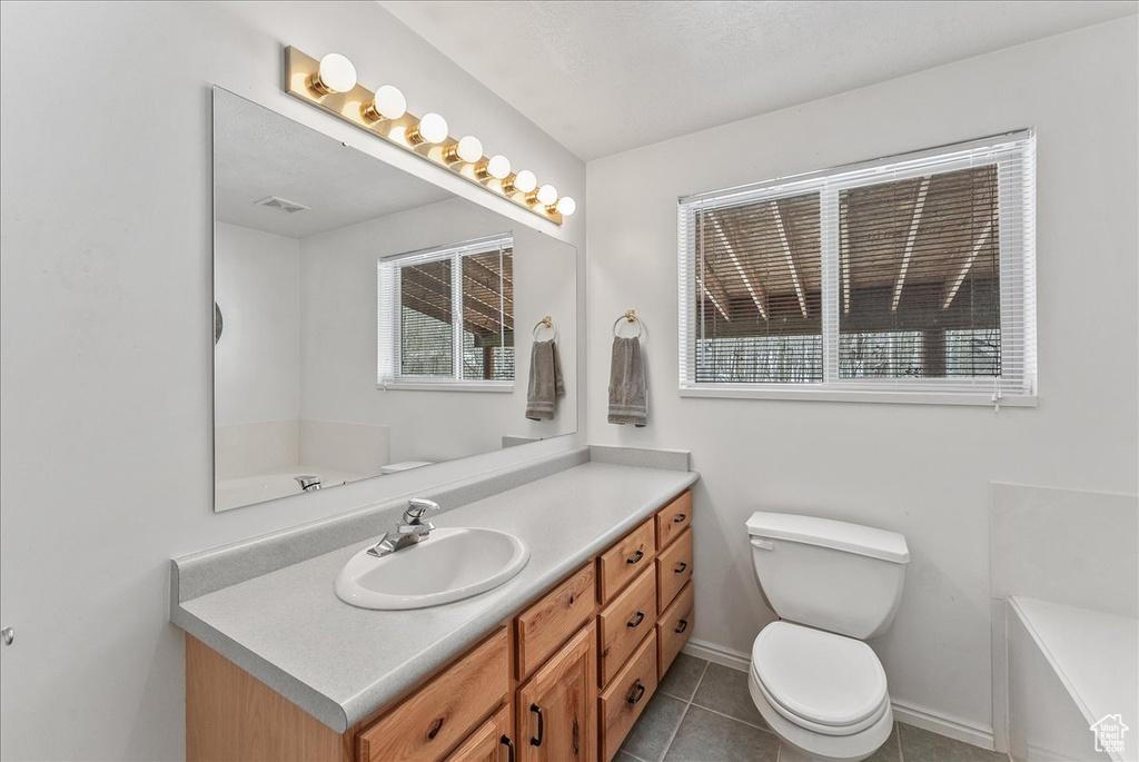 Bathroom with a bathing tub, toilet, tile flooring, and vanity with extensive cabinet space