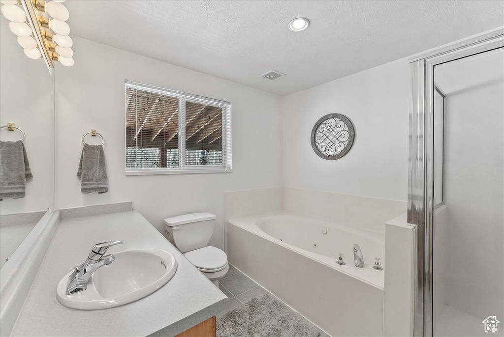 Bathroom with a tub, vanity, tile floors, toilet, and a textured ceiling