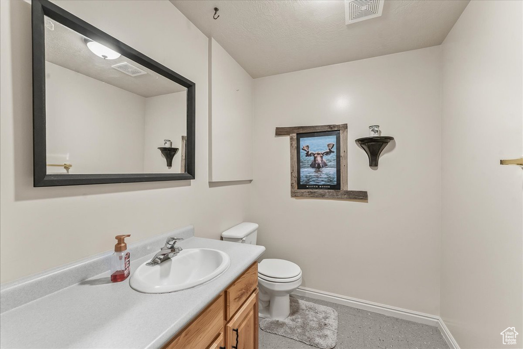 Bathroom featuring a textured ceiling, vanity, and toilet