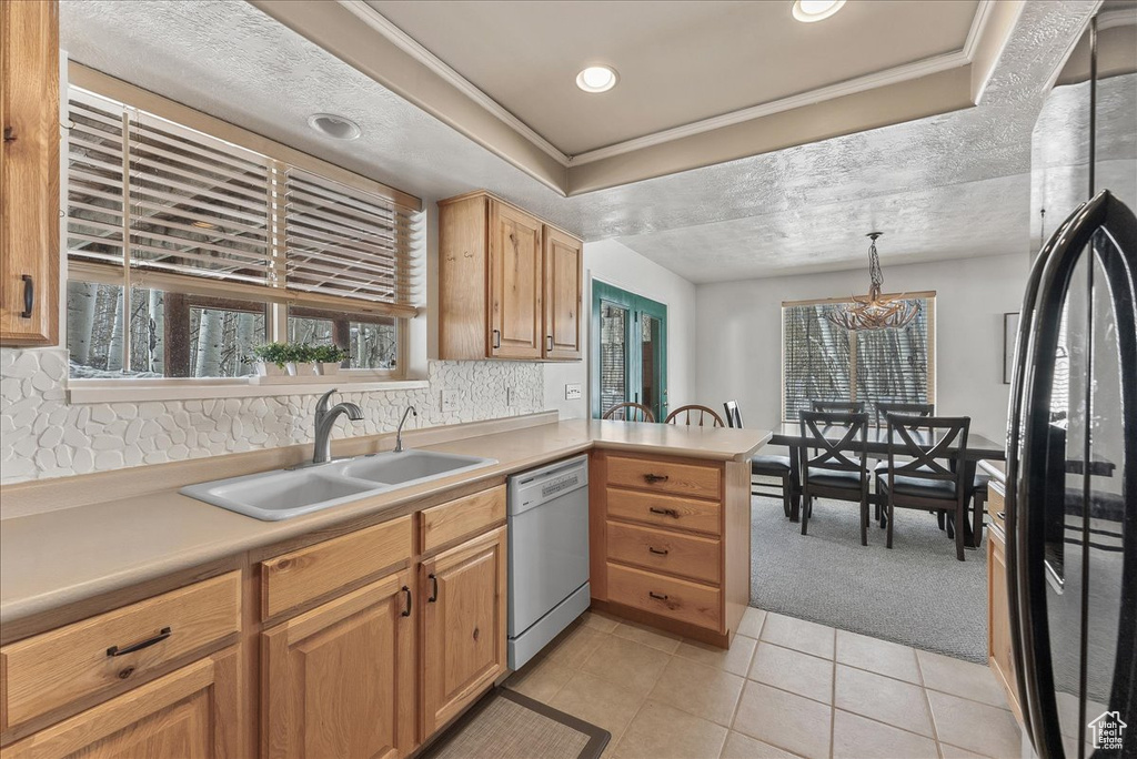 Kitchen featuring pendant lighting, sink, white dishwasher, black refrigerator, and light colored carpet