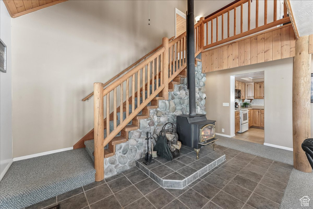 Stairs featuring high vaulted ceiling, a wood stove, tile floors, and wooden ceiling