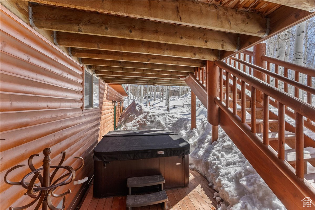 Snow covered deck featuring a hot tub