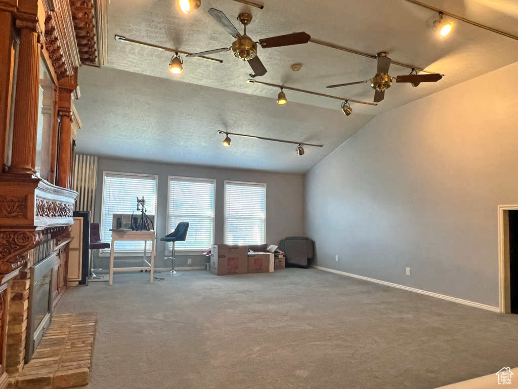Unfurnished living room featuring track lighting, a textured ceiling, ceiling fan, and carpet floors