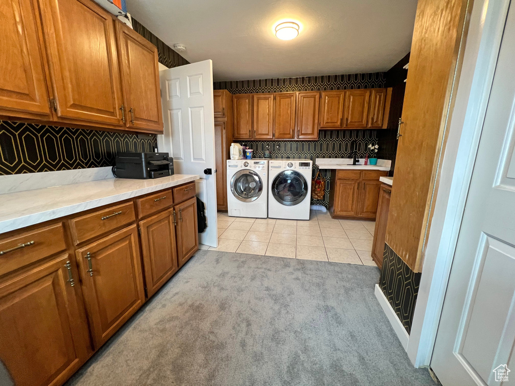 Laundry room featuring separate washer and dryer, sink, cabinets, and light tile floors