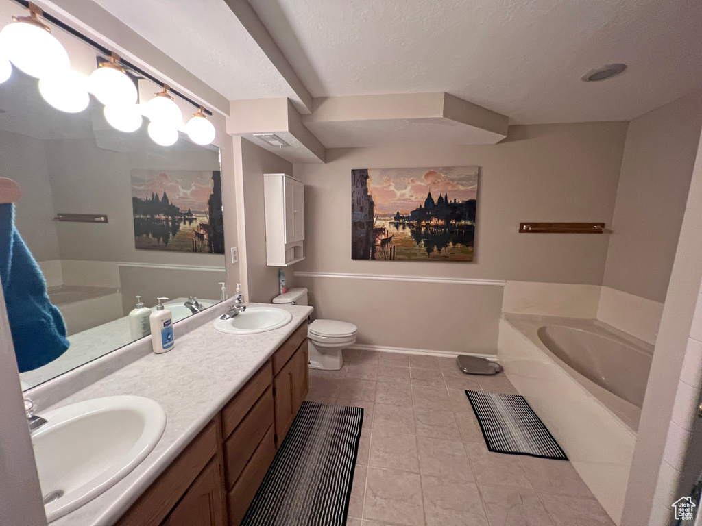 Bathroom with tile flooring, double vanity, a textured ceiling, a bathing tub, and toilet